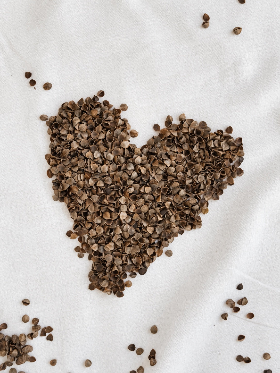 Buckwheat hulls arranged in a heart shape on white linen